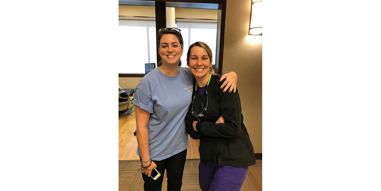 Two dental team members in the dental office hallway