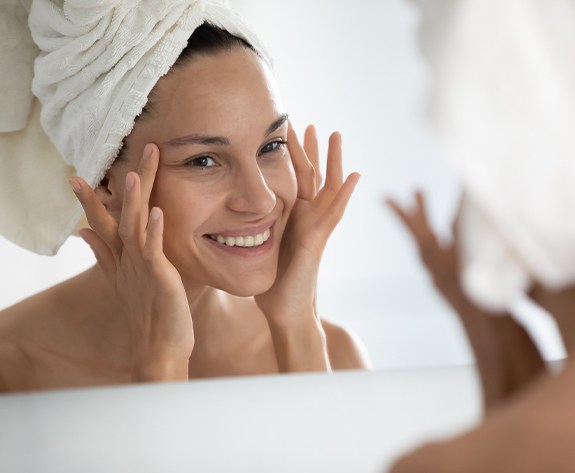 Woman admiring her youthful facial appearance after Botox and dermal fillers