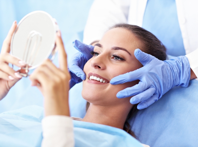 Woman looking at her smile in the mirror during dental treatment