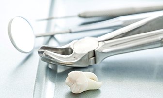 An extracted tooth set next to dental tools