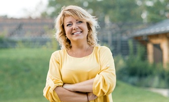 Woman smiling outside while wearing a yellow shirt