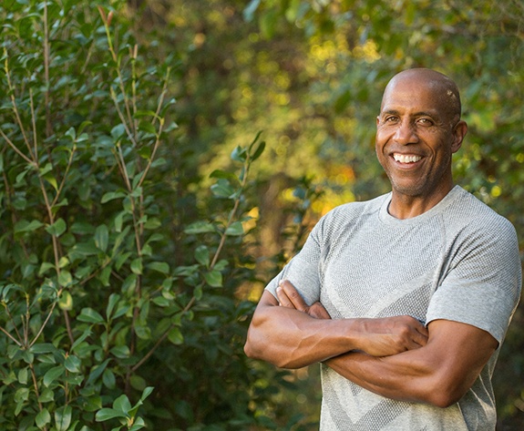 smiling man standing among trees