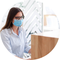 Woman wearing face mask at a dental office reception desk