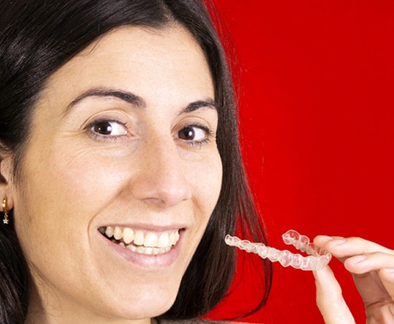 Woman with Invisalign in Greensboro on red background