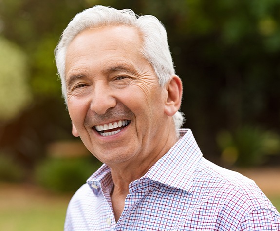 Man with dentures smiling outdoors