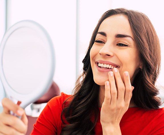 Woman looking at porcelain veneers in mirror