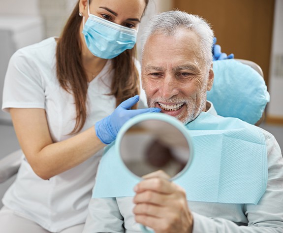 Man looking at smile in mirror after cosmetic dentistry