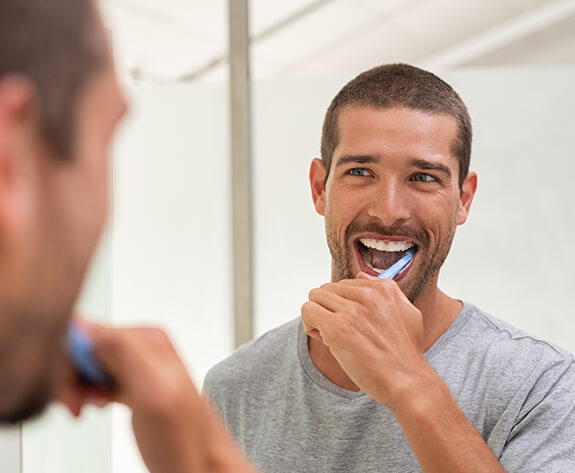 Man brushing teeth to prolong teeth whitening results