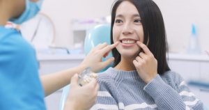 A dentist pointing at a female patient’s smile.