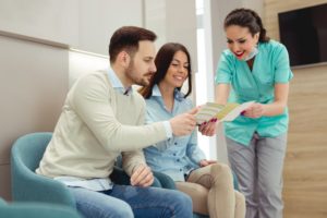 dental team member explaining dental insurance to two patients 