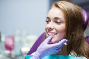 Woman smiling and being checked in dentist's chair. 